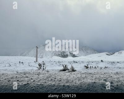 Niedrige Wolken über Berggipfeln mit schneebedeckter Landschaft im Vordergrund, an einem kalten Wintertag, in der Nähe des Ski- und Snowboardresorts Mammoth Lakes, Kalifornien Stockfoto