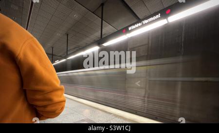 LOS ANGELES, CA, 2022. JANUAR: Der Rand einer Person mit orangefarbenem Sweatshirt steht auf dem Bahnsteig, während der Zug der Roten Linie auf dem U-Bahn-System LA in die Station Wilshire-Vermont fährt Stockfoto