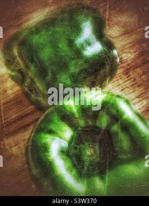 Stillleben Bild eines Paares von grünen Paprika auf einem Holzblock Tisch mit dramatischer Beleuchtung. Grunge-Effekt digital hinzugefügt für künstlerische Wirkung. Stockfoto