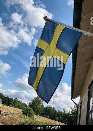 Schwedische Flagge gegen einen wolkigen blauen Himmel Stockfoto