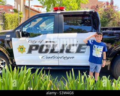 Ein Junge im Urlaub in Kalifornien posiert neben einem Polizeiauto in der Stadt Calistoga. Stockfoto