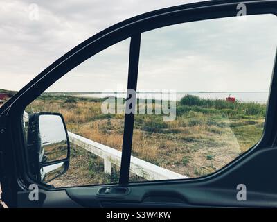 Ein Strand an der Westküste Schwedens an einem bewölkten Tag, der durch ein Fenster auf der Autoseite gesehen wird Stockfoto