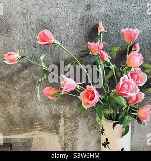 Rosafarbene Rosen an einer strukturierten grauen Wand Stockfoto