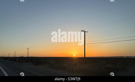 Telegraph Pole und Drähte an der Seite einer Wüste Autobahn in Kalifornien, Silhouetten bei Sonnenuntergang Stockfoto