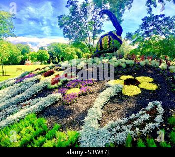 Ein männlicher Pfau im Topiary, draußen in einem öffentlichen Park, Québec, Kanada. Bereit zum Tanzen. Mensch und Natur machen ein tableau. Stockfoto