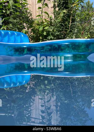 Wasseroberfläche in einem aufblasbaren Pool, der die Pflanzen des umliegenden Gartens reflektiert Stockfoto