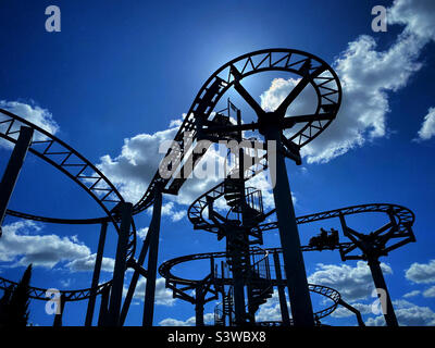 Zwei Personen auf einer Achterbahnfahrt genießen den Nervenkitzel und die Verschüttungen an einem heißen Sommertag. Foto ©️ COLIN HOSKINS. Stockfoto