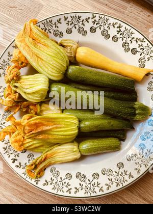 Baby Zucchini mit Blumen auf dem Teller Stockfoto