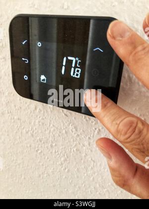 Eigenheimbesitzer, der den Gaszentralheizraumthermostat niedriger anpasst, um auf den spiralförmigen Treibstoffkosten und den Lebenshaltungskosten zu sparen Stockfoto