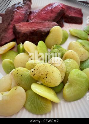 Nahaufnahme einer Mahlzeit mit mittelseltenen Steaks und frisch gedämpften lima-Bohnen, 2022, USA Stockfoto