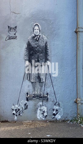 Queen Elizabeth II reitet auf einem Hover Board, während sie mit 3 Corgi-Hunden spazieren geht. Ein berühmtes Graffiti-Kunstwerk von „catman“ in der High Street in Whitstable in Kent. Foto ©️ COLIN HOSKINS. Stockfoto