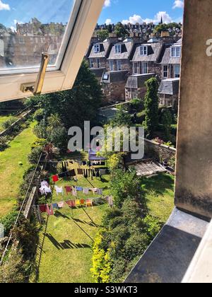 Kleidung hängt bis zum Trocknen auf einer Wäscheleine in einem Vorstadtgarten hinten Stockfoto