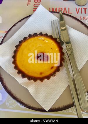 Portugiesische Pudding-Tarte auf weißem Gewebe und Teller mit Messer und Gabel. Stockfoto