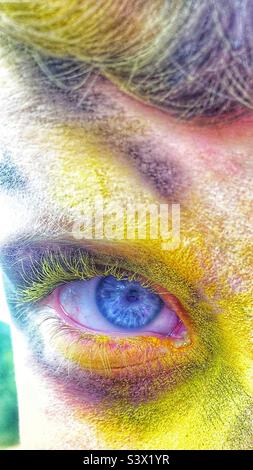 Hellblaues Auge auf dem Gesicht mit Pulverfarbe bedeckt, hauptsächlich gelbe Nahaufnahme Stockfoto