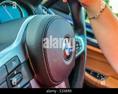 Frau, die das BMW-Auto aus nächster Nähe fährt Stockfoto
