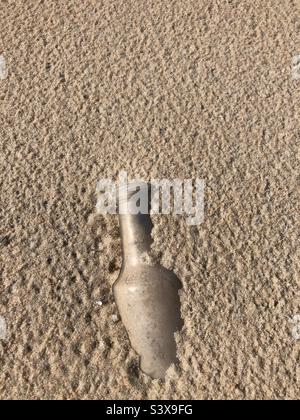 Eine Flasche, die halb im Sand vergraben ist. Stockfoto