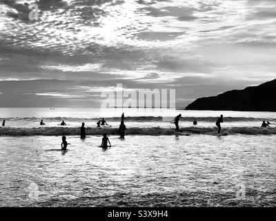 Surfer sitzen auf ihren Brettern und warten in Devon England auf Wellen Stockfoto