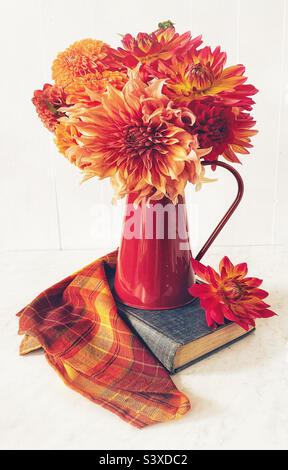 Blumenstrauß von herbstlichen Dahlien in einem roten Krug aus Metall. Stockfoto