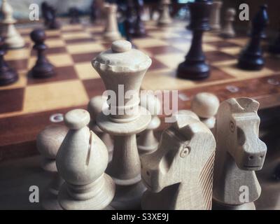 Schachfiguren, die während eines Spiels auf einem Brett im Hintergrund genommen wurden Stockfoto