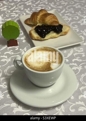 Grünes Frühstück mit Bio-Cappuccino, Bio-Croissant und Sauerkirschmarmelade Stockfoto