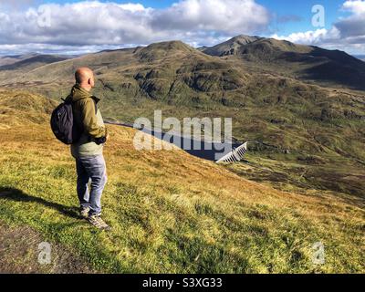 Walker auf dem Pfad zum Tarmachan Ridge mit Blick auf die Ben Lawers Bergkette und den Lawers Damm, Killin, Schottland Stockfoto