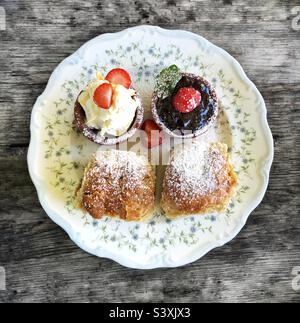 Flaches Essen im Hintergrund eines kornischfarbenen Cremetees mit Scones, Erdbeermarmelade und gerinnter Creme auf einem Vintage-Teller Stockfoto