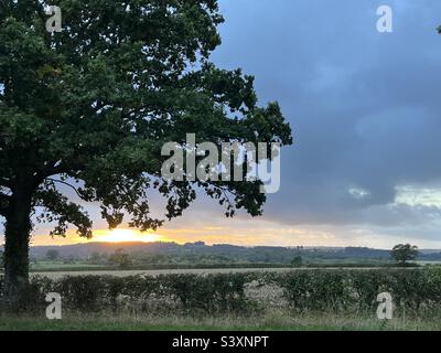 Sonnenuntergang über den Gloucestershire Feldern vor stürmischem Himmel Stockfoto