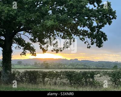 Sonnenuntergang über den Gloucestershire Feldern vor stürmischem Himmel Stockfoto