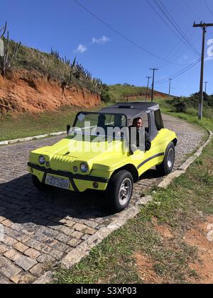 Ein Mann, der einen leuchtend gelben Dünenbuggy fährt. Stockfoto