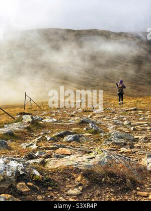 Weibliche Walker auf dem Weg und den Hängen von Munro Stuc an Kette, im Nebel und niedrige Wolke, Glen Lyon, Schottland Stockfoto