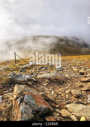 Weibliche Walker auf dem Weg und den Hängen von Munro Stuc an Kette, im Nebel und niedrige Wolke, Glen Lyon, Schottland Stockfoto