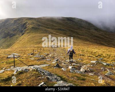 Weibliche Walker auf dem Weg und den Hängen von Munro Stuc an Kette, im Nebel und niedrige Wolke, Glen Lyon, Schottland Stockfoto