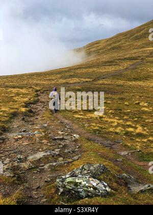 Weibliche Walker auf dem Weg und den Hängen von Munro Stuc an Kette, im Nebel und niedrige Wolke, Glen Lyon, Schottland Stockfoto