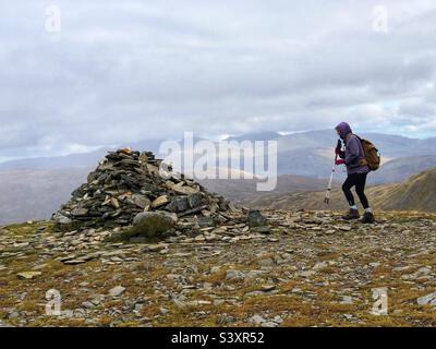 Walkerin auf dem Grat, der sich dem Gipfelsturm von Munro Meall Buidhe, Glen Lyon, Schottland, nähert. Stockfoto