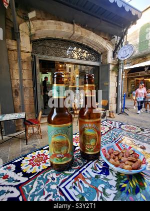 Genießen Sie das palästinensische Taybeh Bier im Abu ATA Zaman Café in der Nähe des Neuen Tores in der Altstadt von Jerusalem. Stockfoto