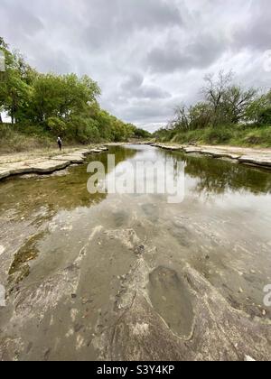 Wandern entlang des Flussufers und Zählen von Dinosaurierfußabdrücken im Kalkstein. Gelegen im Dinosaur Valley State Park Texas Stockfoto