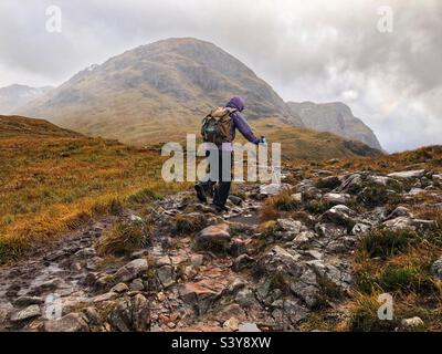 Weibliche Walkerin auf dem Weg und den Hängen von Munro Buachaille Etive Beag, Glencoe, Schottland Stockfoto