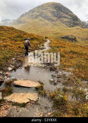 Weibliche Walkerin auf dem Weg und den Hängen von Munro Buachaille Etive Beag, Glencoe, Schottland Stockfoto