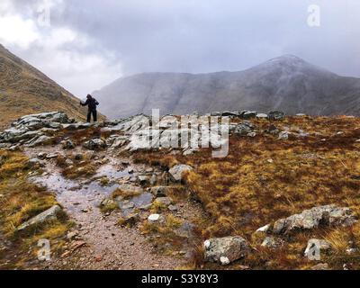 Weibliche Walkerin auf dem Weg und den Hängen von Munro Buachaille Etive Beag, Glencoe, Schottland Stockfoto