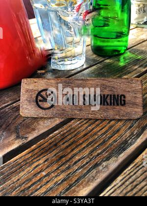 Ein hölzernes Rauchverbot-Schild auf dem Außentisch eines Cafés mit Platz für Kopien Stockfoto