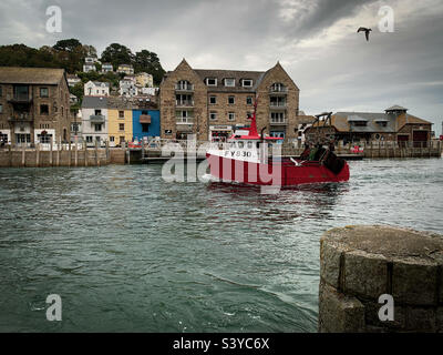 Ein Fischerboot fährt den Fluss hinauf zum Kai im Hafen von Looe, Cornwall, Großbritannien Stockfoto