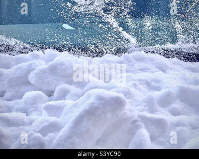 Eine sehr saisonale, winterliche Zusammenfassung, aufgenommen nach einem Schneesturm in Utah, USA. Die unteren zwei Drittel des Bildes sind Schnee auf der Motorhaube des Autos, während das obere Drittel die „meist“ von der Windschutzscheibe freigeschüttet ist. Stockfoto