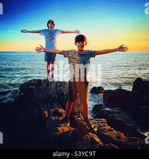 2 Freunde stehen am Meer und haben ihre Arme weit geöffnet Stockfoto