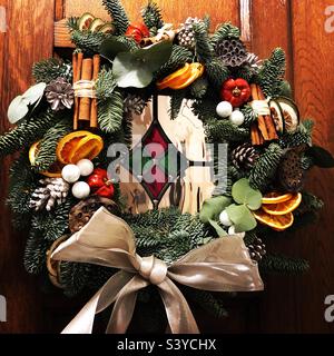 Weihnachtskranz an Holztür mit Buntglas Stockfoto