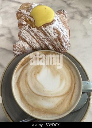 Typisch italienisches Frühstück an der Bar mit Cappuccino und Croissant gefüllt mit chantilly-Creme Stockfoto