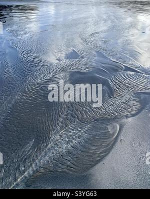 Wellen im seichten Wasser am Sandstrand Stockfoto