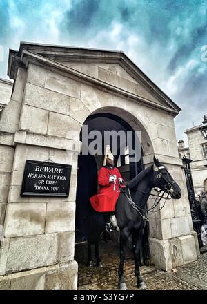 Der King's Life Guard wird von Soldaten des „Household Cavalry Mounted Regiment“ in Horse Guards, Whitehall London, geleitet. Schild liest Vorsicht Pferde können treten oder beißen! Stockfoto