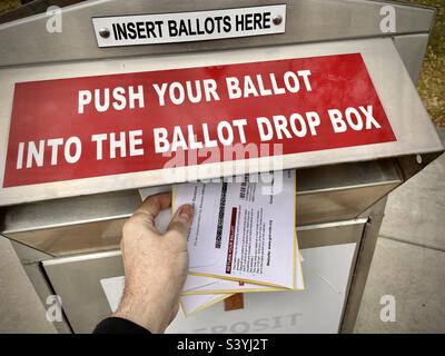 Eine lokale Wahlurne in Utah, in der Nacht vor den Zwischenwahlen in den Vereinigten Staaten im November 2022. Die Hand einer Person wird gesehen, wie sie am Abend des Wahltages die Stimmzettel seiner Familie an einem lokalen Drop-Box abgibt Stockfoto