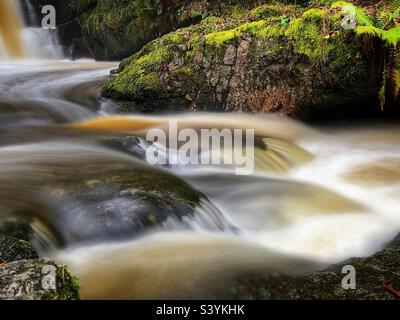 Weiches, verschwommenes Wasser, das über moosige Felsen fließt, Brecon Beacons, Wales. Stockfoto