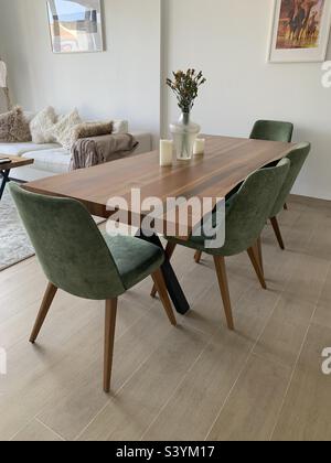 Stilvoller Esstisch aus Holz mit grünen Stühlen in einem offenen Wohnzimmer Stockfoto